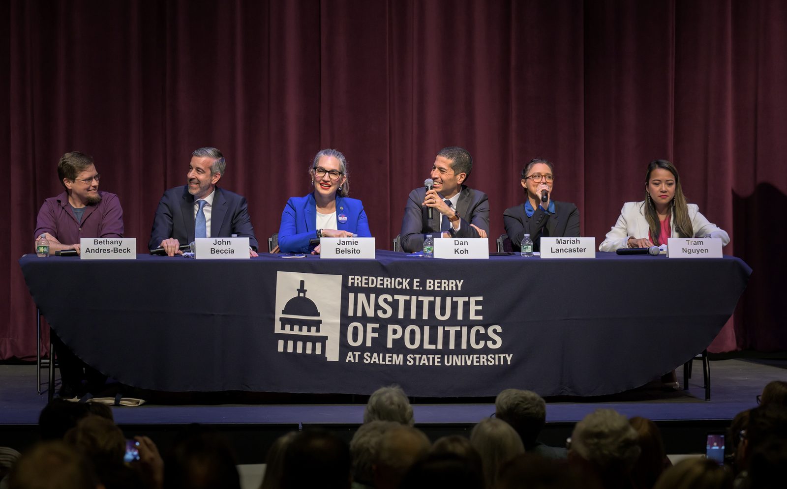 The six MA-06 Democratic candidates seated at a debate panel at Salem State University: Bethany Andres-Beck, John Beccia, Jamie Belsito, Dan Koh, Mariah Lancaster and Tram Nguyen.